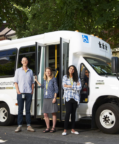 Woodgreen care workers stand outside a Woodgreen bus.