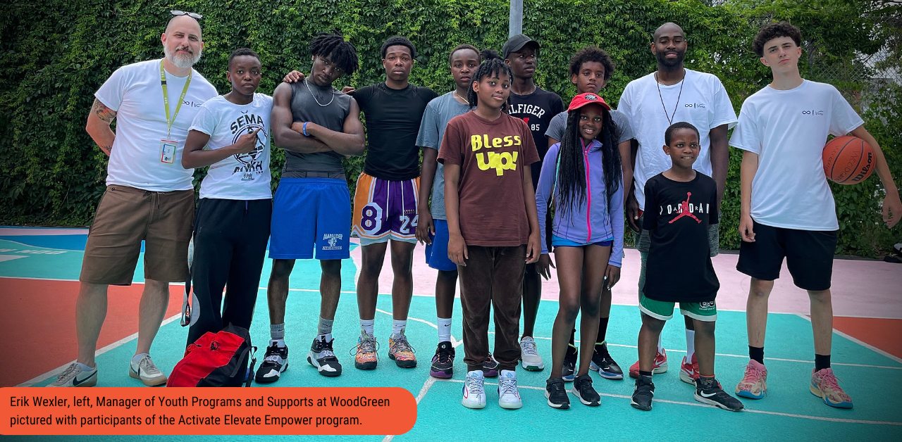 Erik Wexler, Manager of Youth Programs and Supports at WoodGreen, stands with a group of youth on a basketball court.