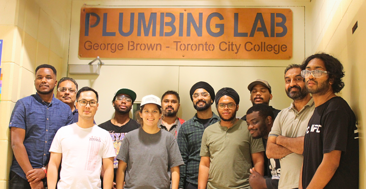 A group stands in front of a sign for the George Brown Plumbing Lab